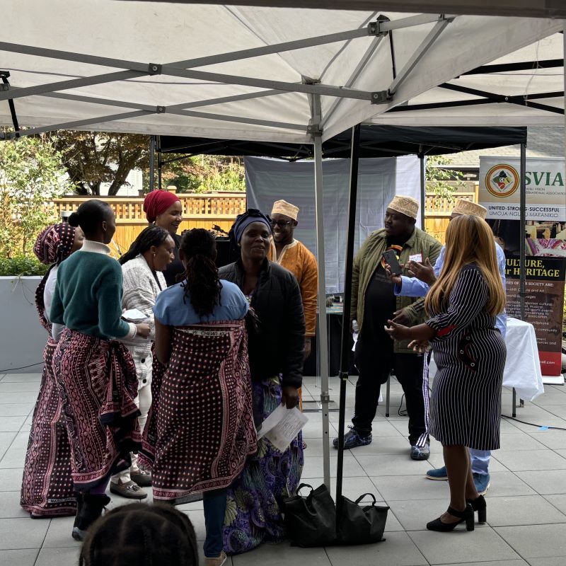 Several mean and women are assembled, many in traditional East African ceremonial clothing on the patio of Móytel Lalém.