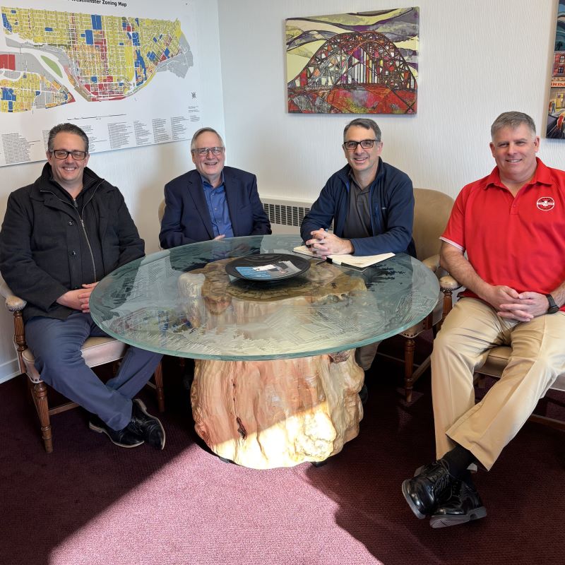 Four middle aged white dudes sit around a table. 